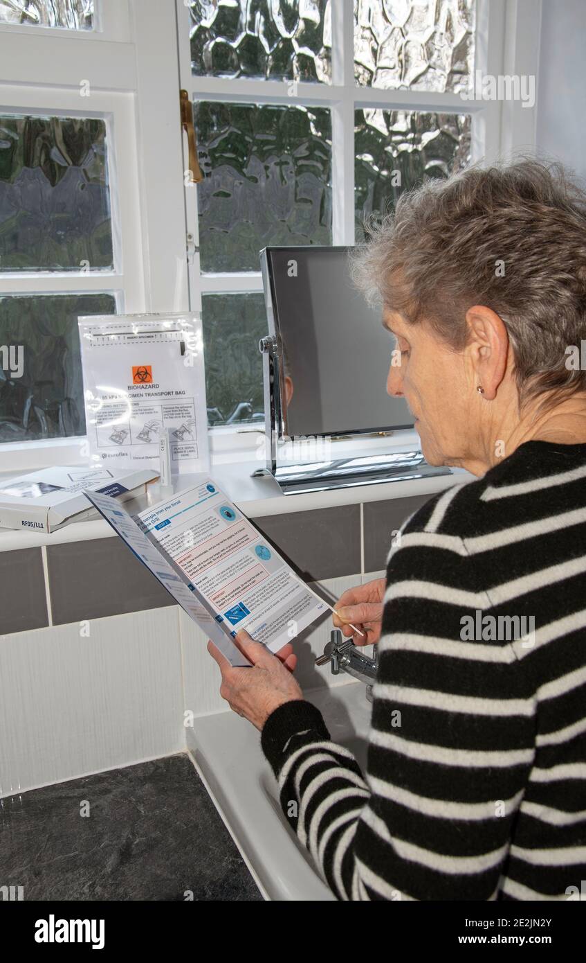 England, Großbritannien. 2021. Frau im Badezimmer studiert die Anweisungen eines Coronavirus, Covid-19 Home Test Kit Stockfoto