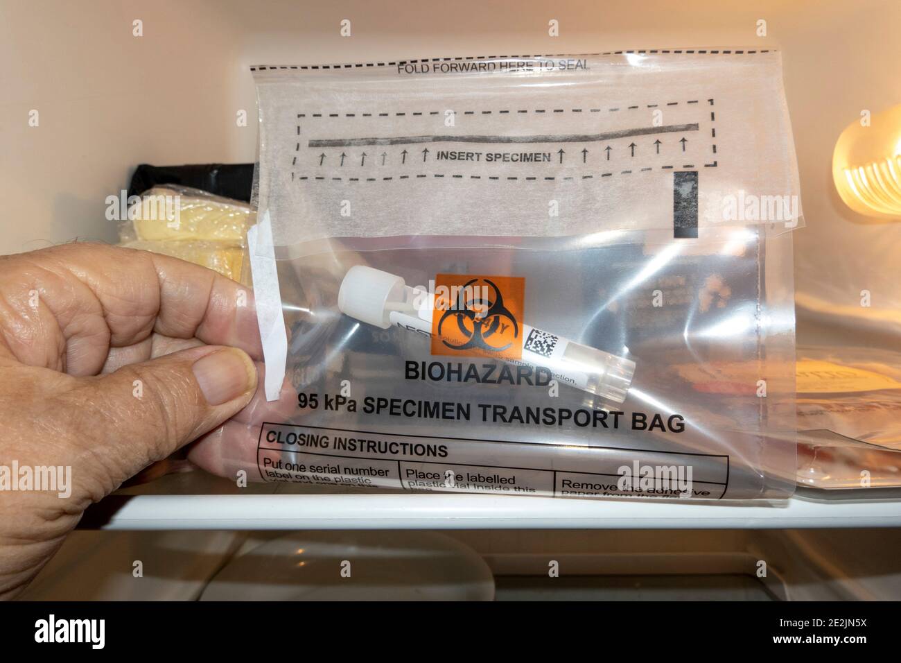 England, Großbritannien. 2021. Coronavirus-Testabstrich in einem Plastikröhrchen, das in einem biohazaierten Beutel in einem Kühlschrank enthalten ist, um kühl zu bleiben, bevor es für Tests gesammelt wird. Stockfoto