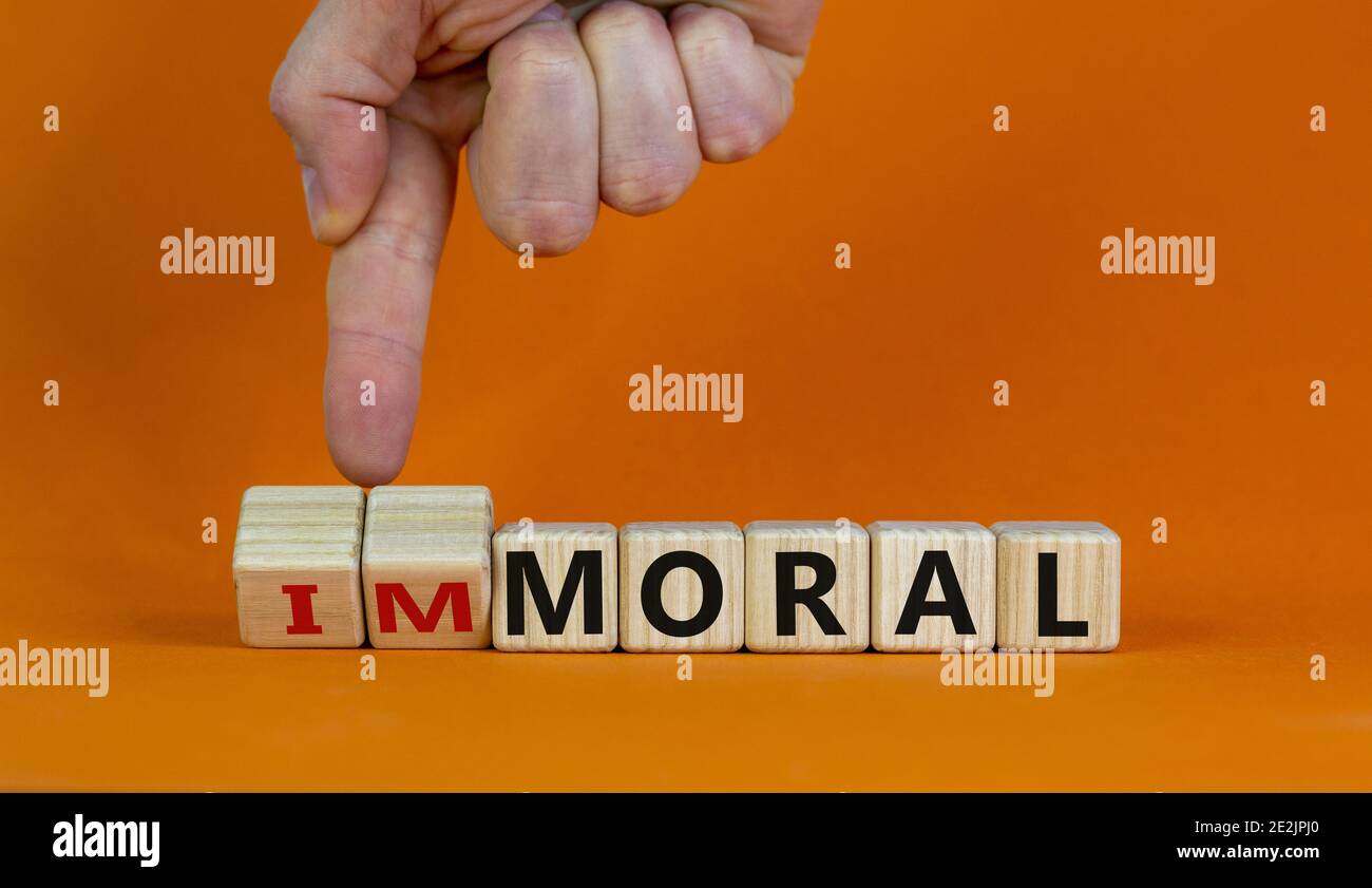 Moralisches oder unmoralisches Symbol. Hand dreht Würfel und ändert das Wort "unmoralisch" in "oral". Schöner orangefarbener Hintergrund. Business und moralische oder unmoralische concep Stockfoto