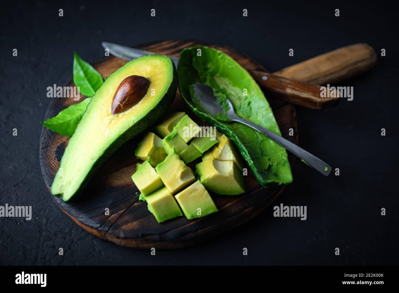 Frische Avocado-Früchte auf einem Holzbrett mit Löffel und Messer. Das Konzept der gesunden Ernährung. Food-Fotografie Stockfoto