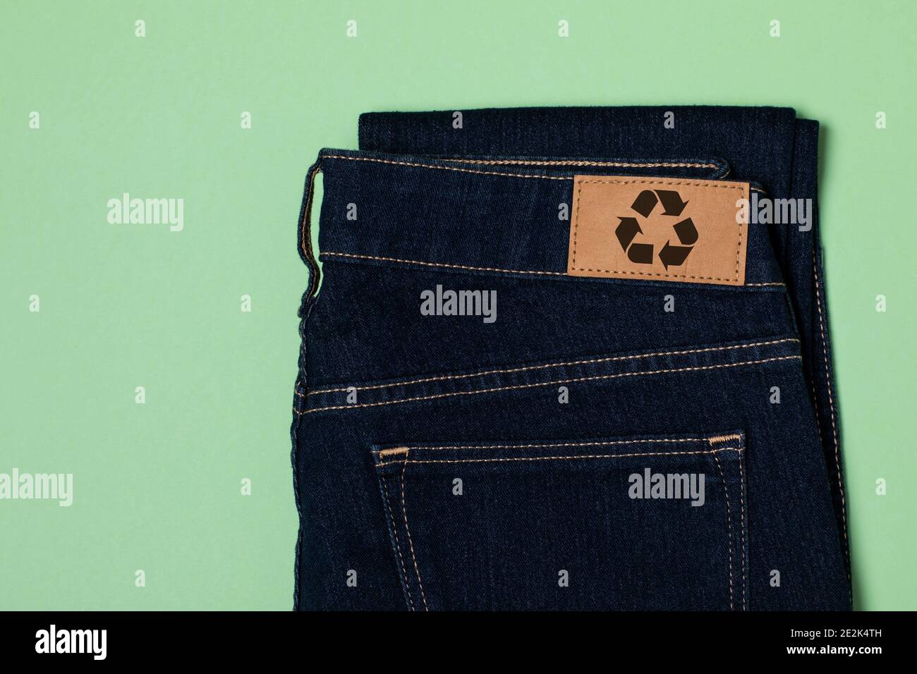 Recycelte blaue Jeans mit einem Bekleidungslabel. Kreisförmiges Economy-Logo, Zero Waste-Konzept. Wiederverwendung von Materialien und Reduzierung von Abfall in der Mode. Denim Horizonta Stockfoto