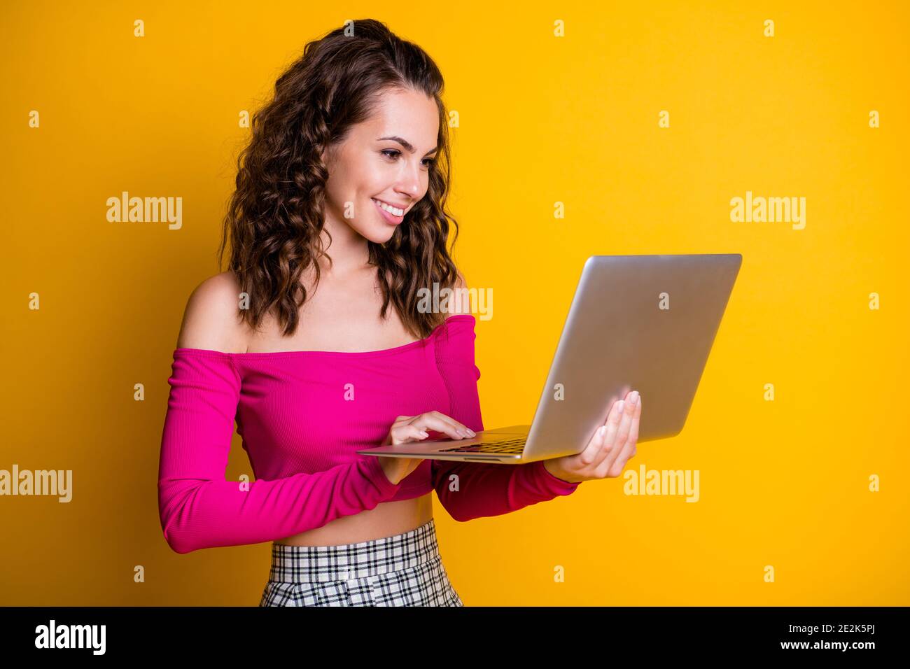 Foto von niedlichen süßen Dame lockig Frisur halten Netbook glänzend Strahlend Lächeln Check Mailbox tragen rosa Top unbekleidet Schultern Rock Isolierte gelbe Farbe Stockfoto