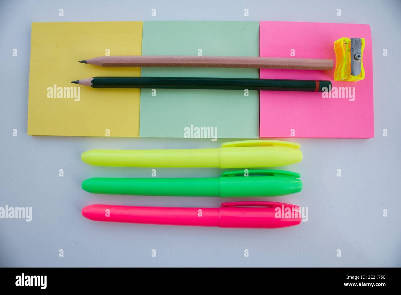 Drei Blocknoten, zwei Stifte und drei bunte Marker. Stockfoto