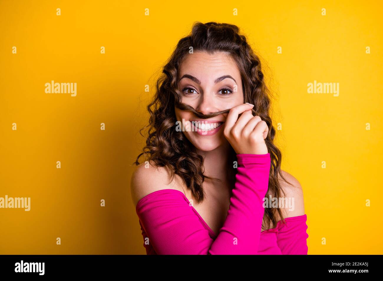 Foto-Porträt von goofy Mädchen machen Haar Schnurrbart lächelnd halten Mit handgetragenem rosa Crop-Top isoliert auf lebhaft gelb gefärbt Hintergrund Stockfoto