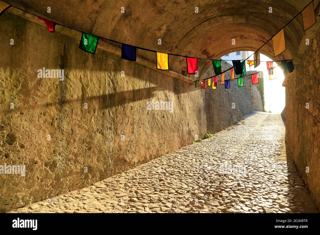 Tunnel durch Felsen mit Fahnen gehangen. Stockfoto