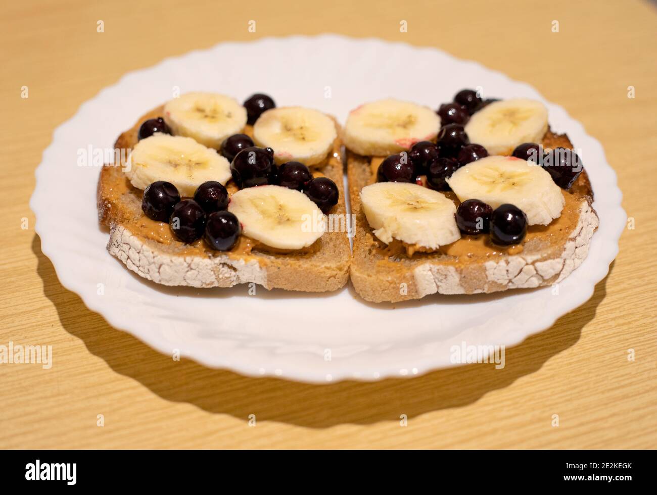Ein gesundes Dessert zum Frühstück, Mittag- oder Abendessen dunkles Brot mit Erdnussbutter, schwarzer Johannisbeere und Bananenscheiben Stockfoto