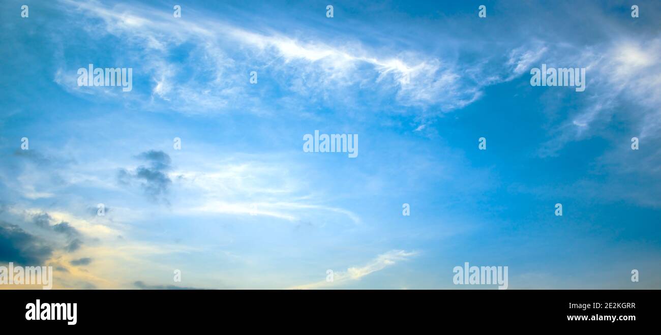 Panoramafoto heller Frühlingsuntergang mit blauem Himmel, weißen Wolken und roter Sonne. Stockfoto