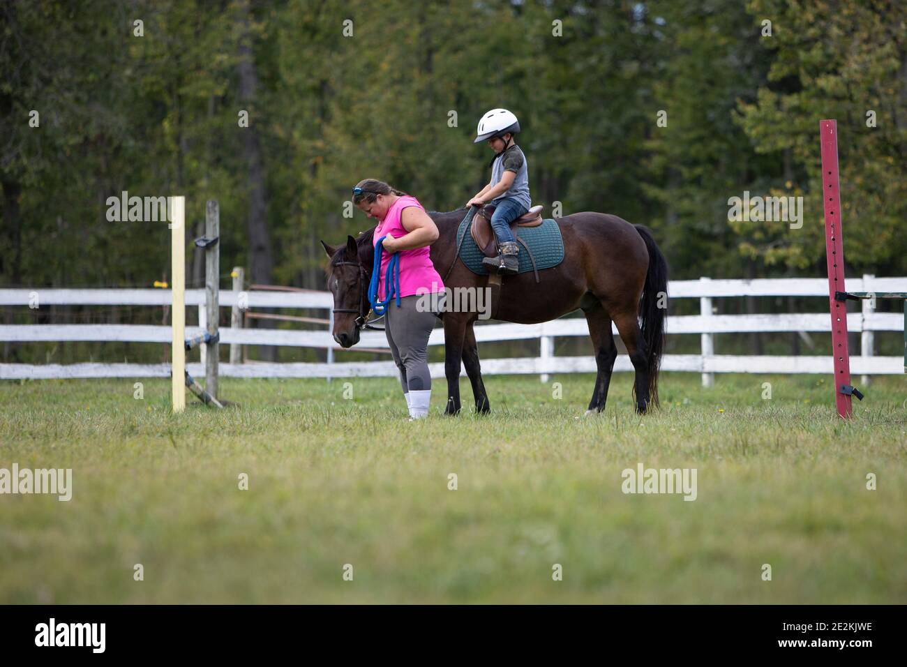 Junge Reiten ein Pony mit einem Lehrer. Stockfoto