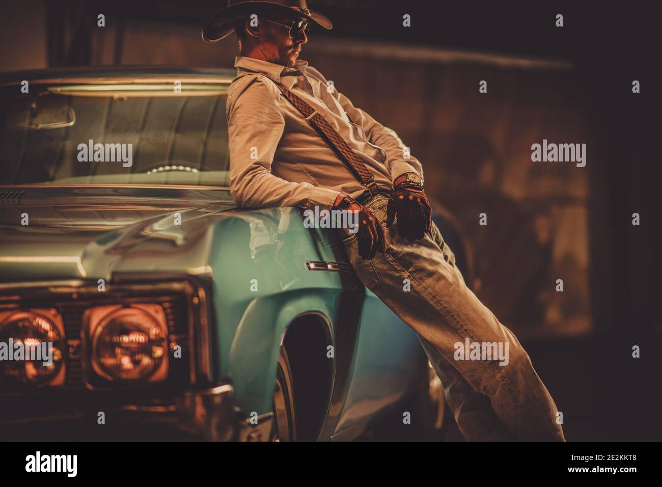 Siebenunddreißig Jahre alter Cowboy trägt Lederhut und Handschuhe im westlichen Stil und sein klassisches Oldtimer. Fahrzeugdesign. Stockfoto