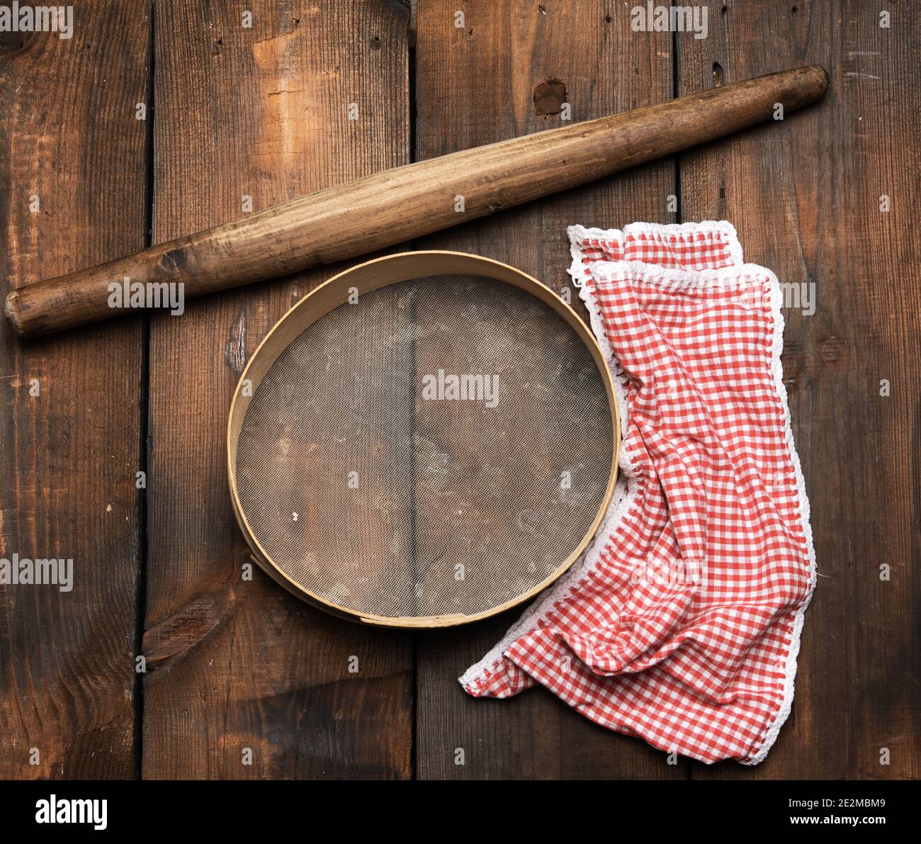 Vintage Holz Nudelholz und ein rundes Sieb, rote Serviette, Draufsicht, Kochutensilien für die Herstellung von Teig Stockfoto