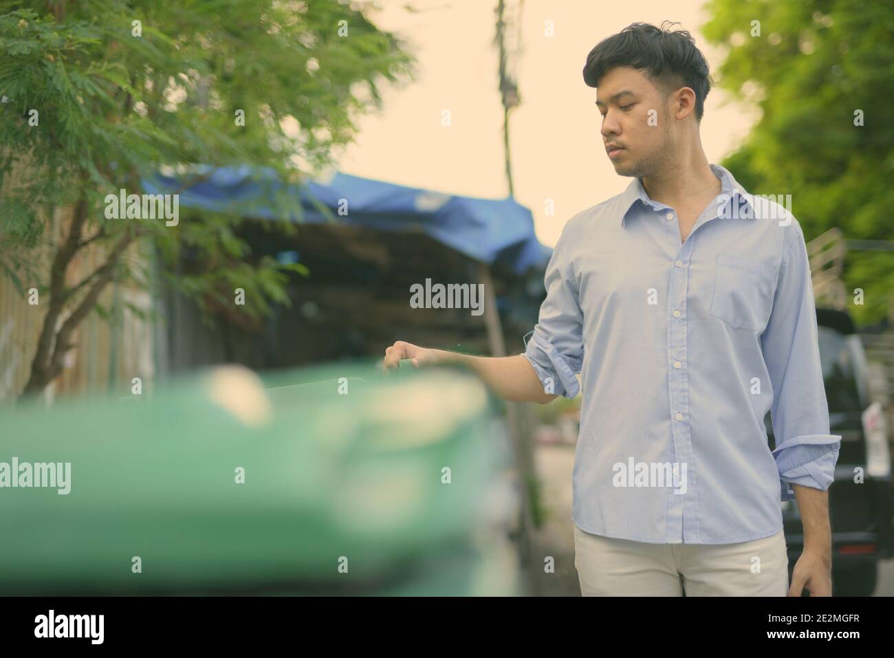 Junger asiatischer Geschäftsmann überprüft den Müll in den Straßen im Freien Stockfoto
