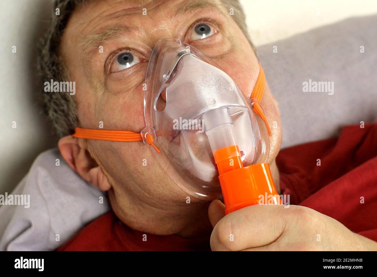 Kranker älterer Erwachsener atmet durch Sauerstoffmaske und rollt die Augen. Behandlung von Asthma, Allergien, Bronchitis, Lungenentzündung bei Covid-19 und Atemschutzmaske Stockfoto