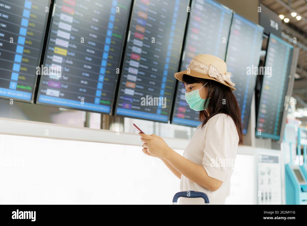Asiatische Frau Tourist tragen Gesichtsmaske Überprüfung Flug von Ankunft Abflug Bord im Flughafen-Terminal für neue normale Reise-Konzept. Stockfoto