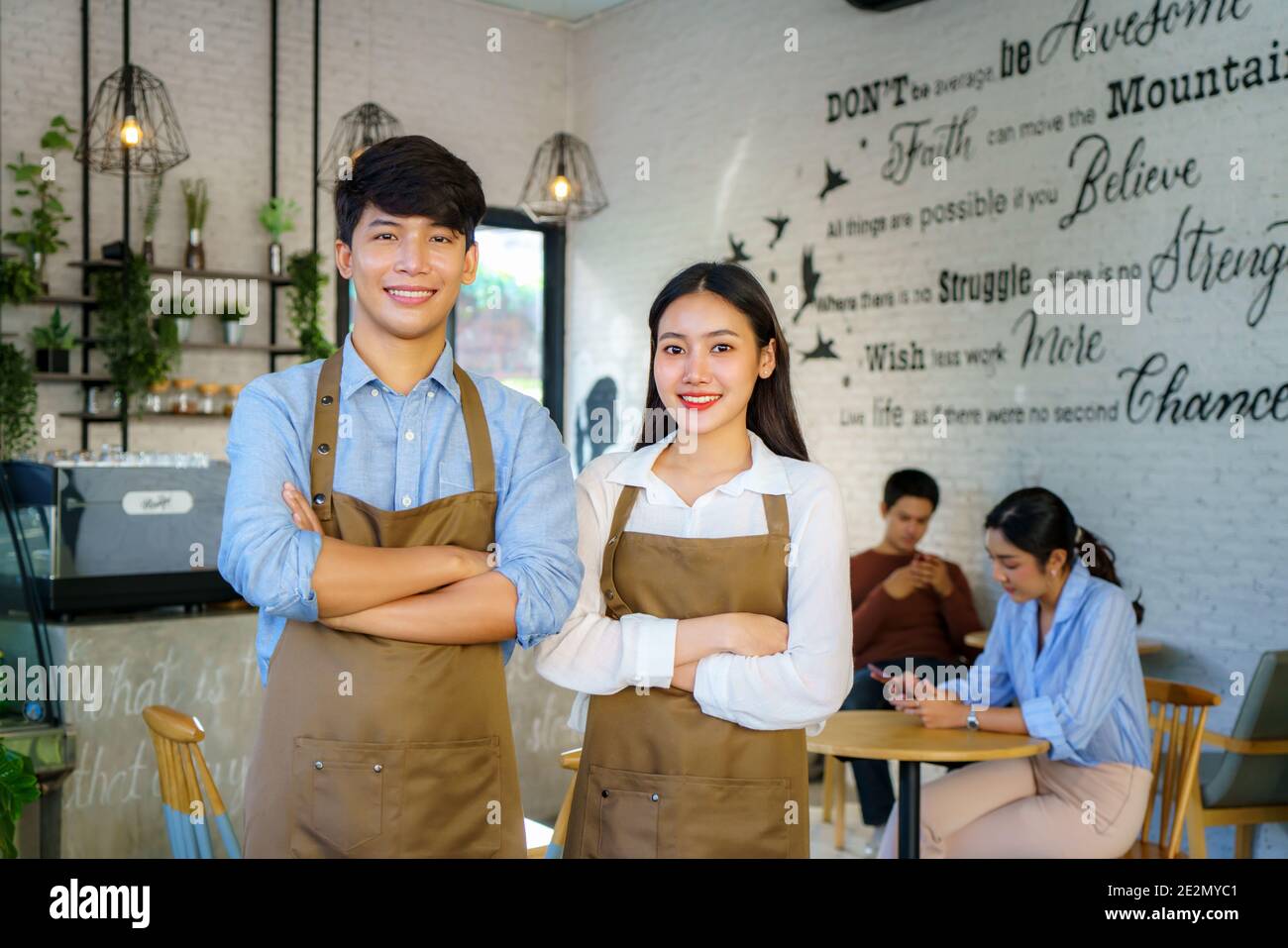 Asiatisches Paar Barista oder Inhaber kleines Unternehmen in Schürze suchen An der Kamera bereit, Kaffee-Service in der modernen geben Café-Bar Stockfoto