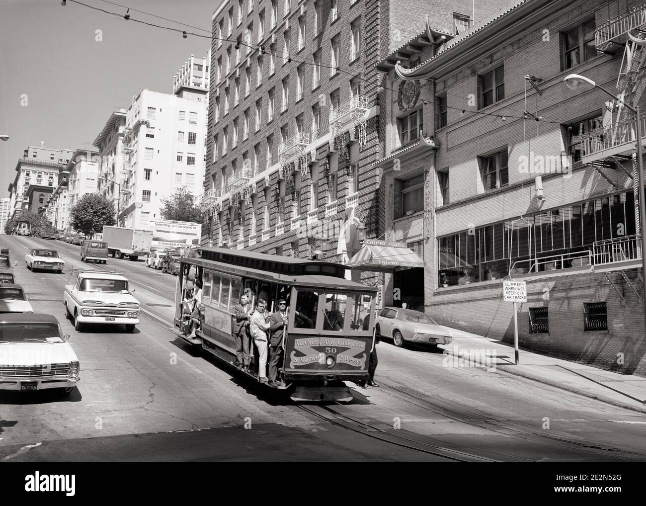 1960 ANONYME PASSAGIERE, DIE DEN BERG HINUNTERFAHREN, HÄNGEN AM STEHEN TRITTBRETTER AUF DER SEILBAHN SAN FRANCISCO CALIFORNIA USA - R21193 HAR001 HARS HILL VEREINIGTE STAATEN RAUM KOPIEREN PERSONEN VEREINIGTE STAATEN VON AMERIKA MÄNNER TRANSPORT BOARDS B&W FRANCISCO NORDAMERIKA NORDAMERIKANISCHE STRUKTUR HOCHWINKEL BERGAB ENTLANG AUFREGUNG AUF CA VERBINDUNG WESTKÜSTE ANONYME SAN FRANCISCO ZUSAMMENARBEIT MEHRERE TRANSIT SCHWARZ UND WEISSES KABEL HAR001 ALTMODISCHE ÖFFENTLICHE VERKEHRSMITTEL Stockfoto