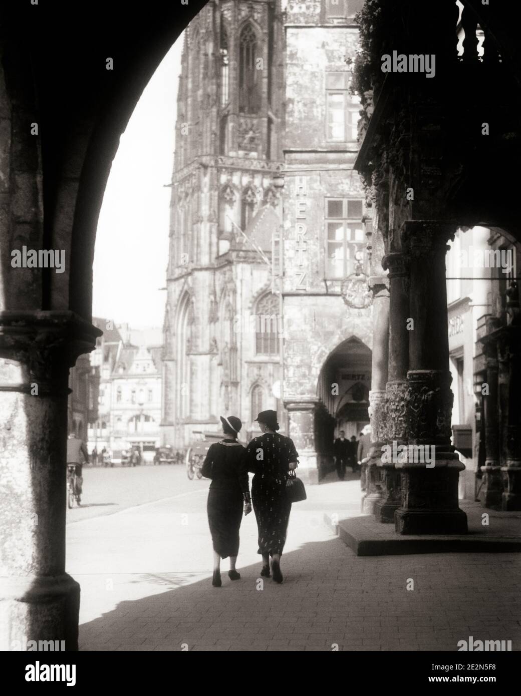 1930ER JAHRE ZWEI ANONYME SILHOUETTEN FRAUEN ZU FUSS IM SCHATTEN EINES BOGEN ZU EINER KIRCHE IM PRINZIPALMARKT MÜNSTER - R6983 HAR001 HARS PERSONS BUILDINGS SILHOUETTEN IN RICHTUNG EUROPA B&W OUTLINE ZEIT AUS STRUKTUR ABENTEUER ARCH EUROPÄISCHEN HOTEL SILHOUETTEN TRIP GETAWAY TOURIST CATHEDRAL URLAUB TOURISTEN IMMOBILIEN MUNSTER STRUKTUREN GEBÄUDE ANONYM URLAUB SCHWARZ UND WEISS HAR001 ALTMODISCH Stockfoto