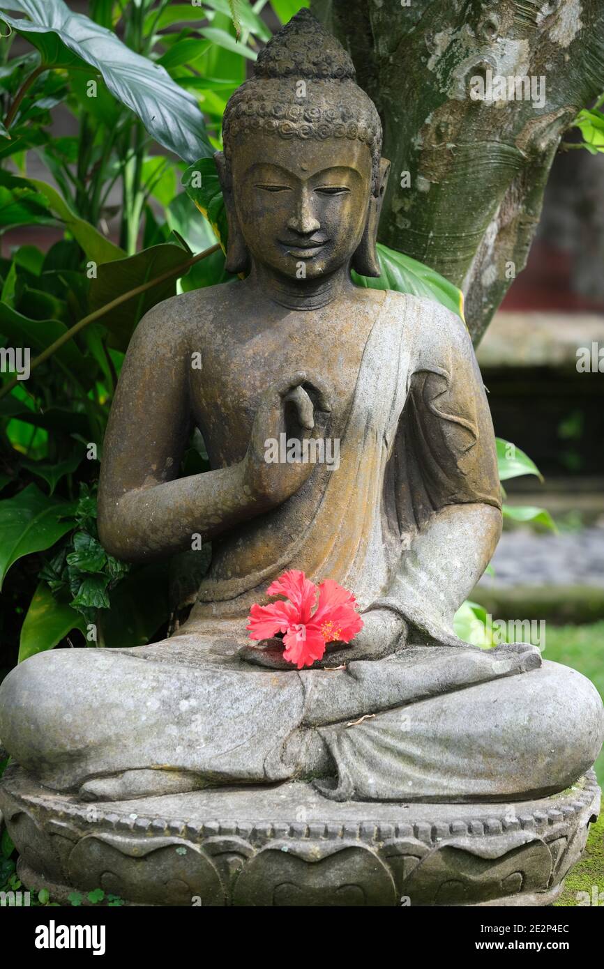 Indonesien Bali - Ubud Handgefertigte Buddha Statue aus Stein mit Hibiskus Blume Stockfoto