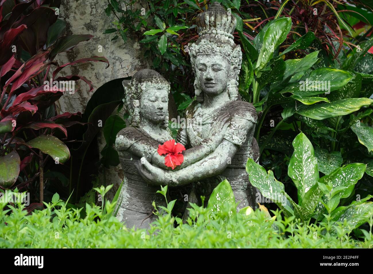 Indonesien Bali - Ubud Handgefertigte Steinstatuen mit rotem Hibiskus Blume Stockfoto
