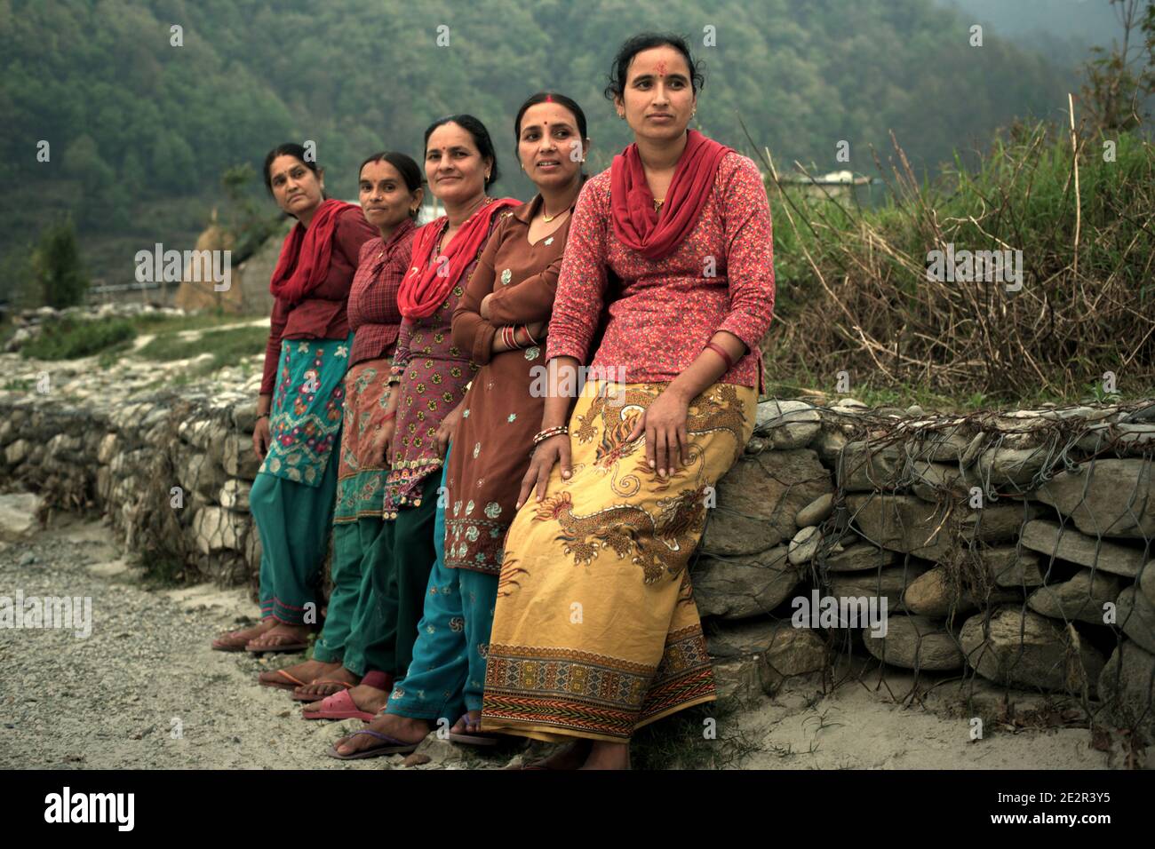 Portrait von Frauen, Dorfbewohnern von Khahare, als sie sich an einer Gabionenwand auf der Seite der Harpan Khola Aue im Kaski Distrikt, Gandaki, Nepal lehnen. Diese Frauen waren Überlebende von Überschwemmungen und Erdrutschen, die durch sintflutartige Regenfälle im Bhaudare Tamagi Gebiet verursacht wurden, wenige Monate nach den Erdbeben von 2015 (April-Mai 2015) in Nepal. Stockfoto