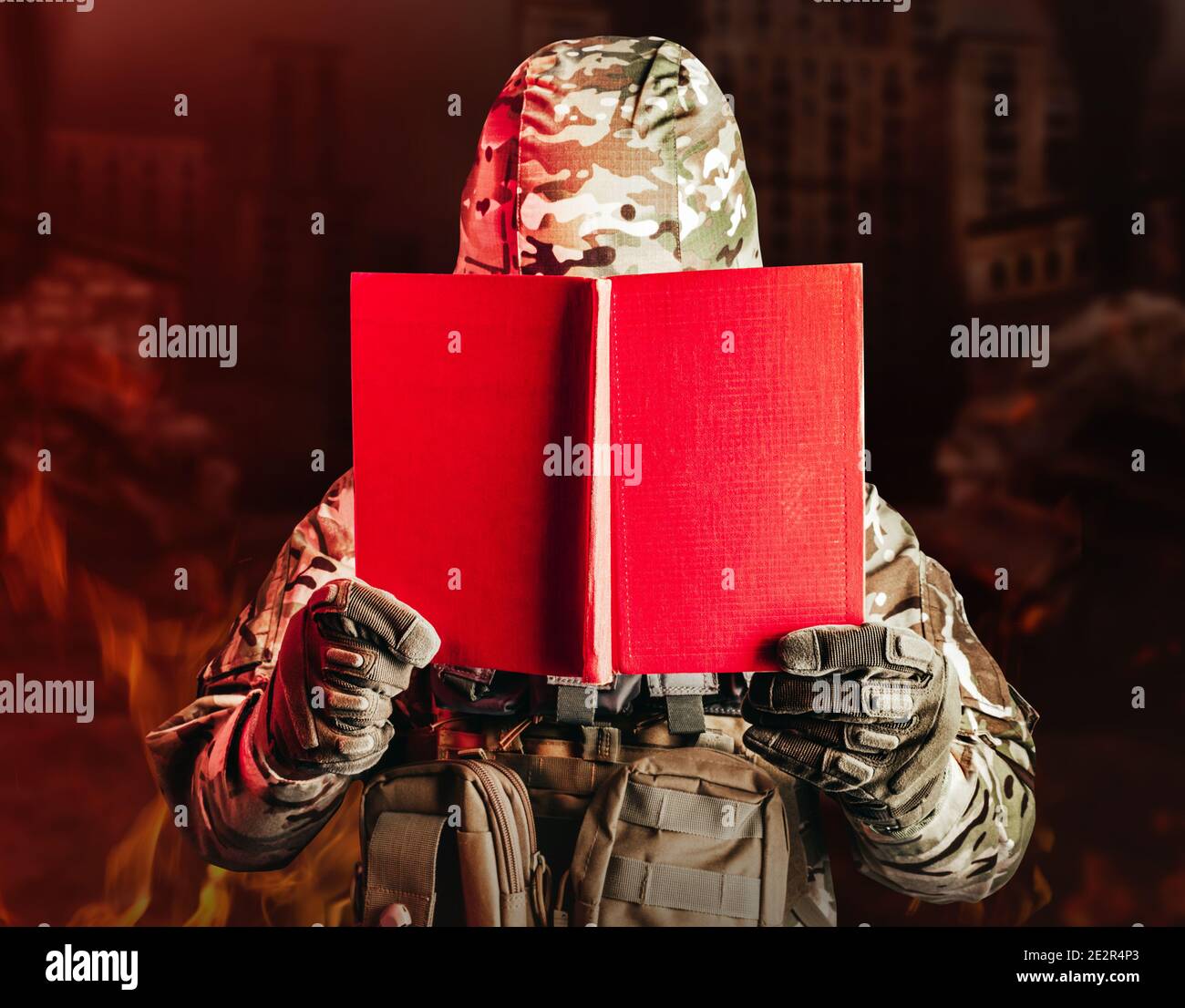 Foto eines Soldaten in Uniform und Rüstung Helm mit geöffnetem roten Buch auf ruinierten Stadt Hintergrund. Stockfoto