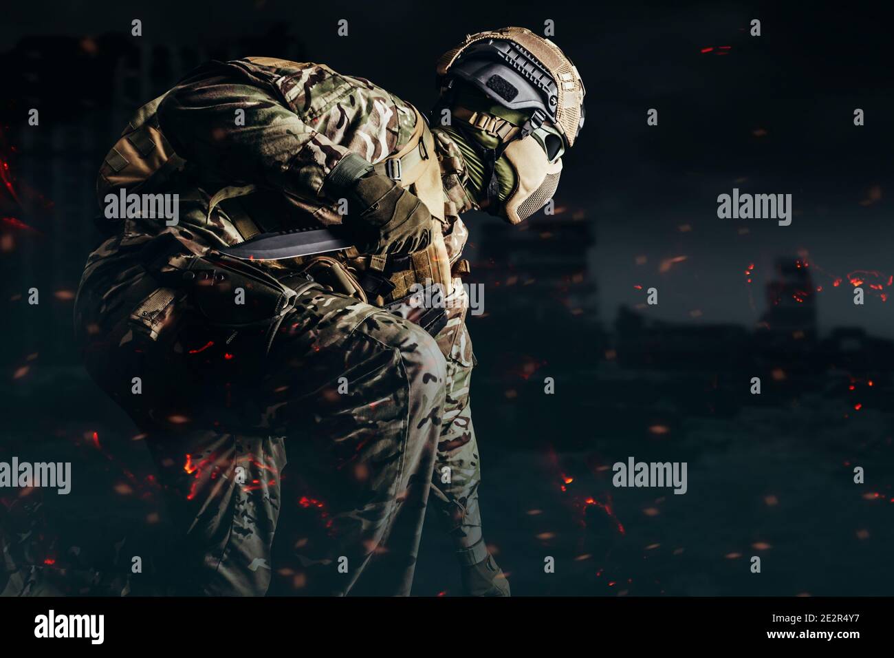 Foto eines voll ausgerüsteten Soldaten in gepanzerter Weste, Helm, Gesichtsbrille und Schutz kniend und Angriff mit Messer auf schattigen zerstörten Stadt Bac Stockfoto