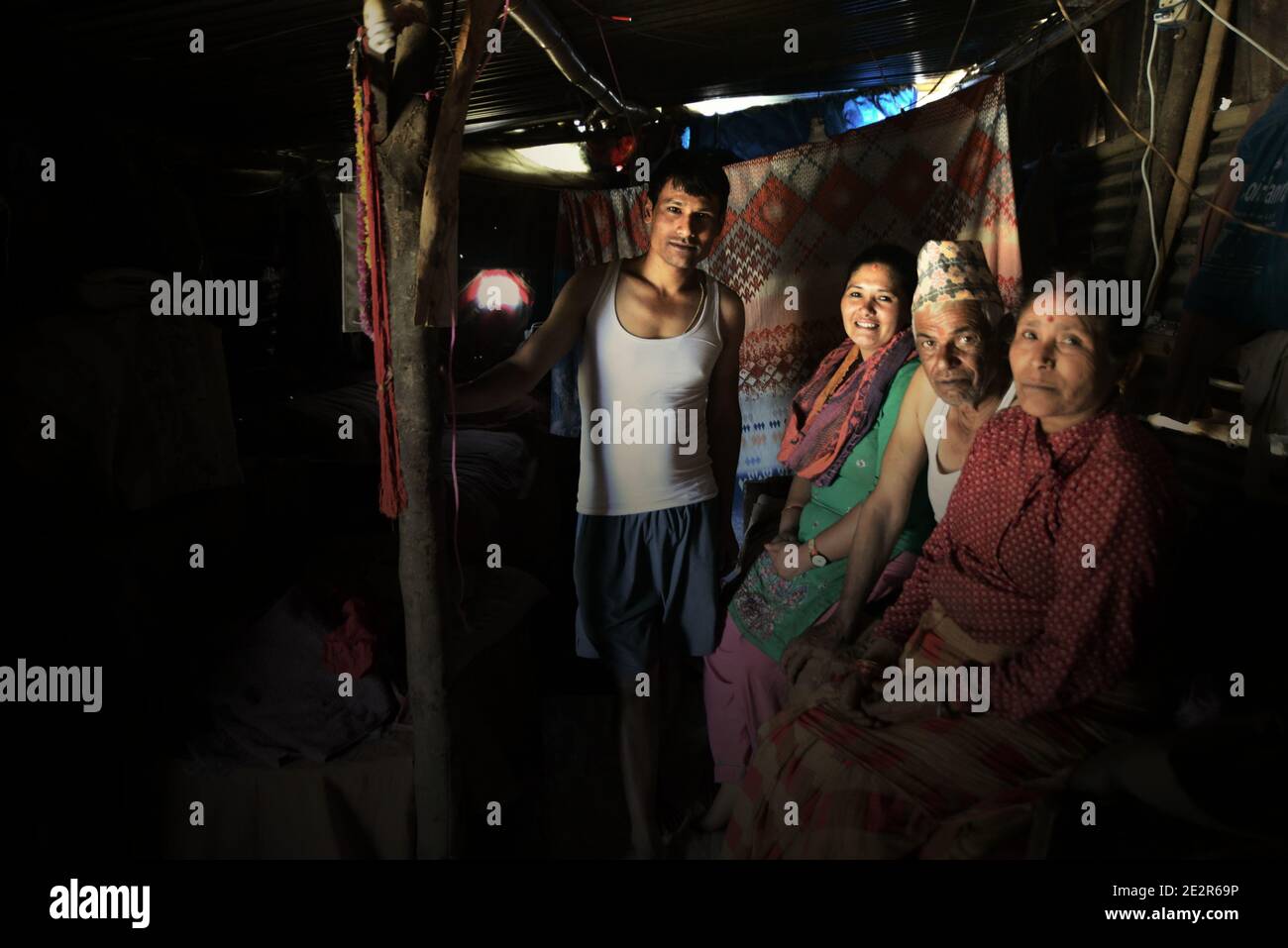 Porträt einer Familie in ihrem temporären Haus am Stadtrand von Bhaktapur, Bagmati, Nepal. Familien, die in ländlichen Gebieten am Stadtrand von Bhaktapur leben, warten darauf, dass ihre neuen Häuser bereit sind, ein Jahr nach den Erdbeben von 2015, die Nepal (April-Mai 2015) heimgesucht haben. Archivfoto (2016). Stockfoto