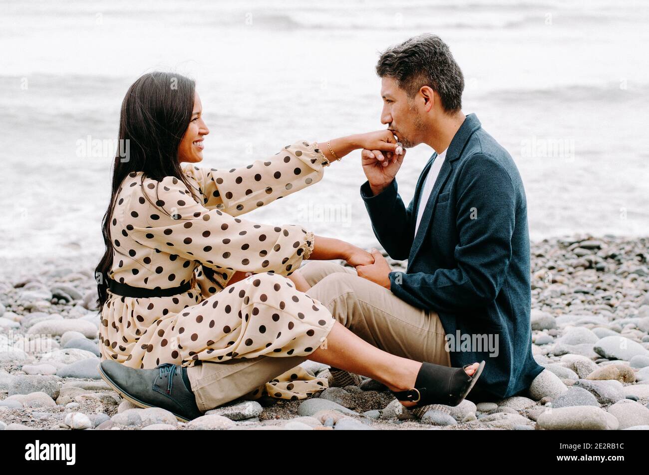 Junges Paar in der Liebe, attraktive Mann und Frau genießen ein romantisches Date am Strand, Mann küssen Frau die Hand Stockfoto