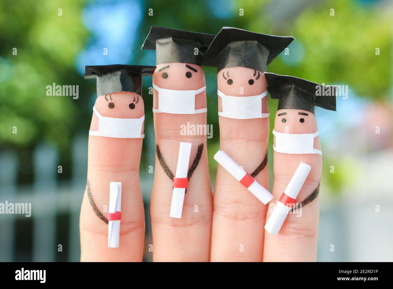 Finger Kunst von Studenten in medizinische Maske aus COVID-2019. Absolventen, die ihr Diplom nach dem Abschluss halten. Stockfoto