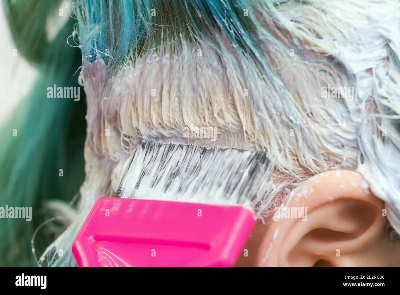 Nahaufnahme des Friseurs mit rosa Pinsel beim Auftragen von Farbe auf  weibliche Kunden mit smaragdgrünen Haarfarbe, während des Prozesses der  Bleichen Haarwurzeln Stockfotografie - Alamy