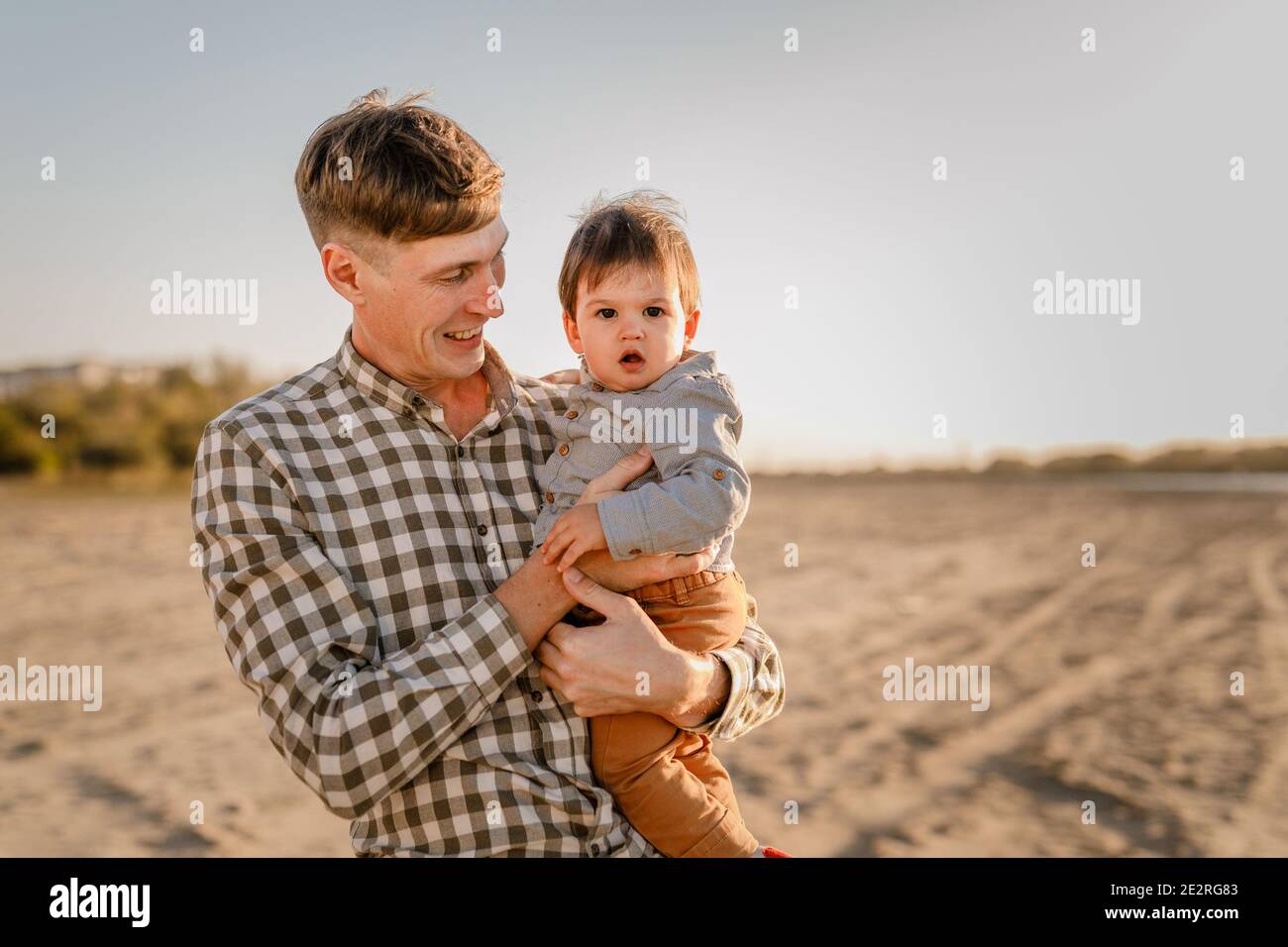 Porträt des liebenden Vaters und seines einjährigen Sohnes, der im Freien läuft und spielt. Stockfoto