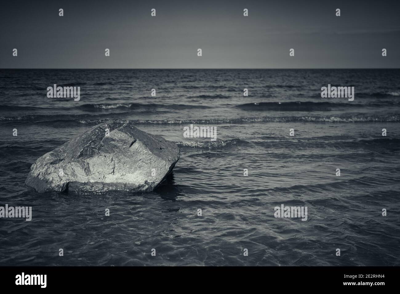 Stein liegt auf einem Meeresboden in seichtem Wasser, Ostsee Küstenlandschaft, blau getönte monochrome Foto Stockfoto