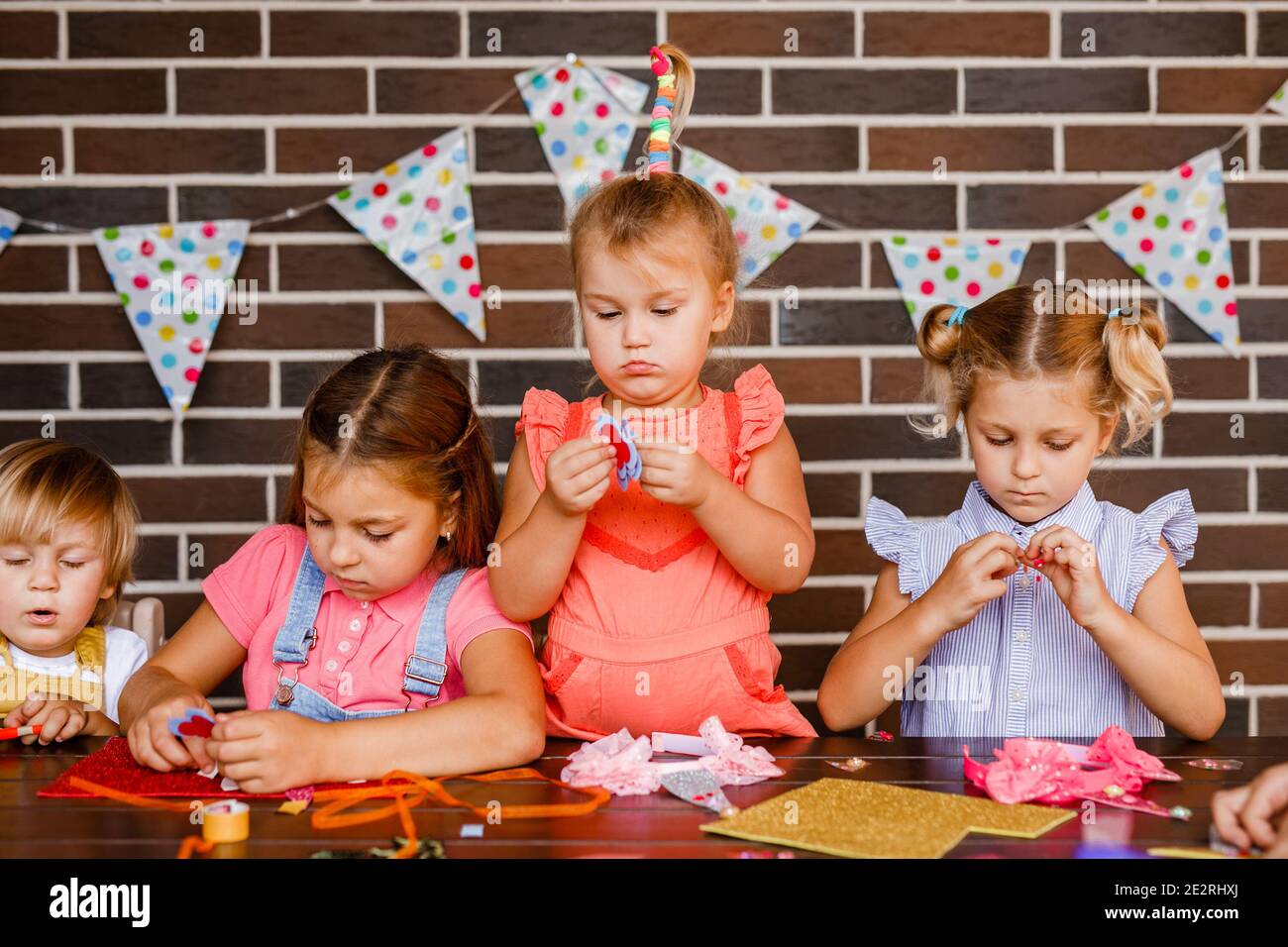 Kleiner Junge m drei Mädchen schneiden etwas aus schönen Papier auf einer Party. Stockfoto
