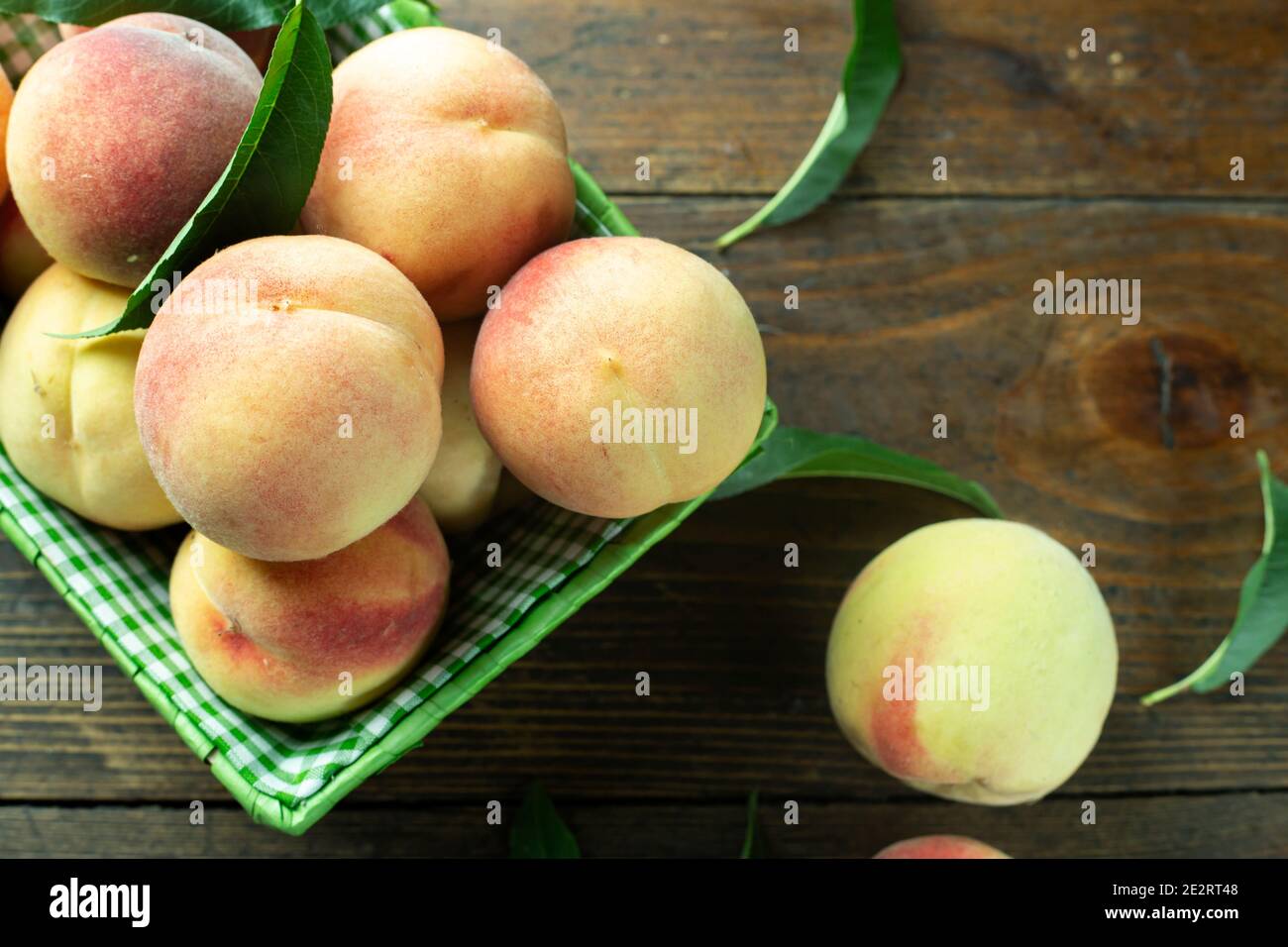 Reife Pfirsiche im Korb auf Holzhintergrund. Hausernte aus dem eigenen Garten. Gesunde Ernährung. Stockfoto