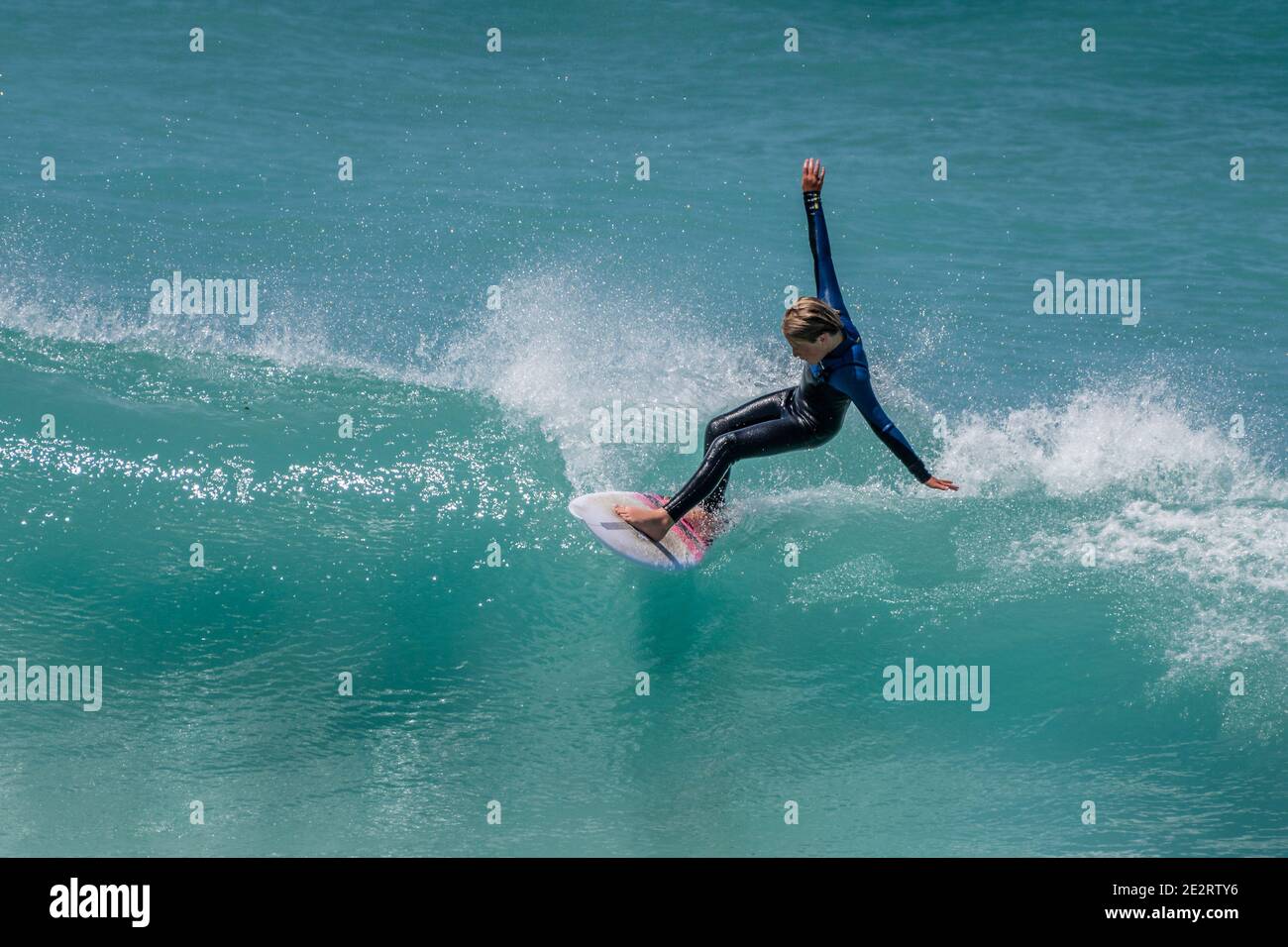 Spektakuläre Action, während ein junger Surfer im Teenageralter eine Welle im Fistral in Newquay in Cornwall reitet. Stockfoto