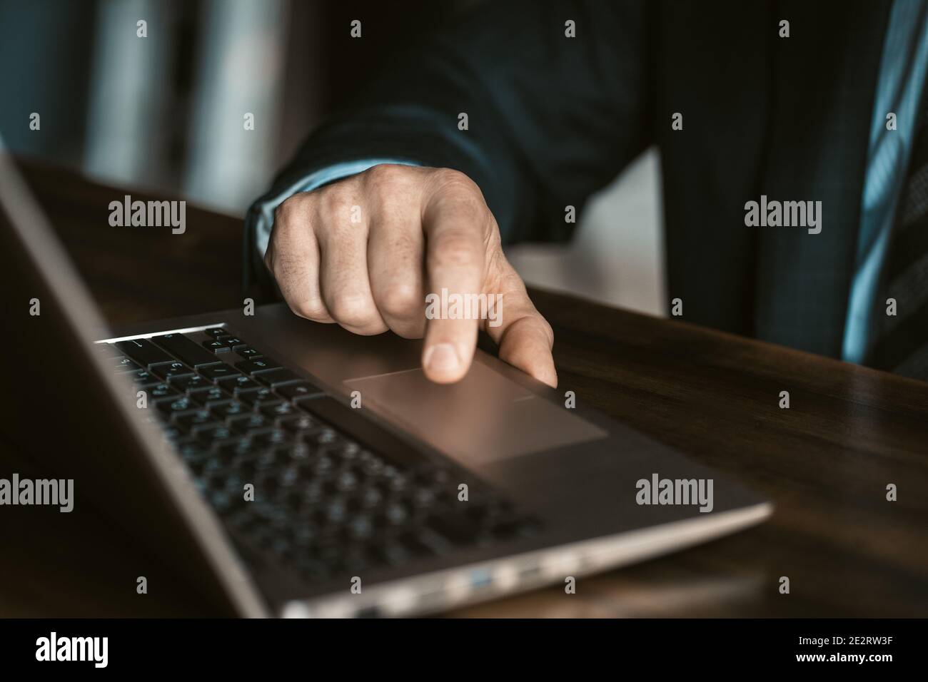 Nahaufnahme. Hände eines Geschäftsmannes in einer teuren Business-Suite, der an einem Laptop im modernen Büro sitzt. Mann, der im Büro an einem Laptop arbeitet Stockfoto