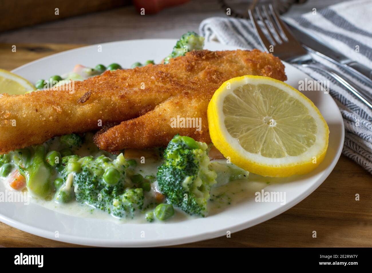 Panierter Fisch mit gemischtem Gemüse in cremiger Sauce Stockfoto