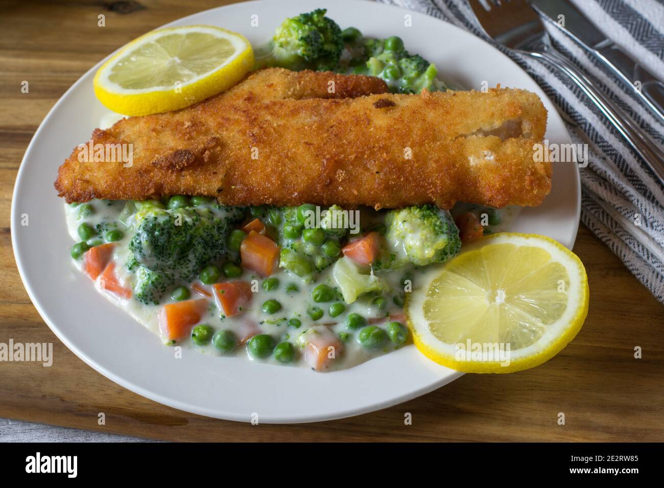 Panierter Fisch mit gemischtem Gemüse in cremiger Sauce Stockfoto