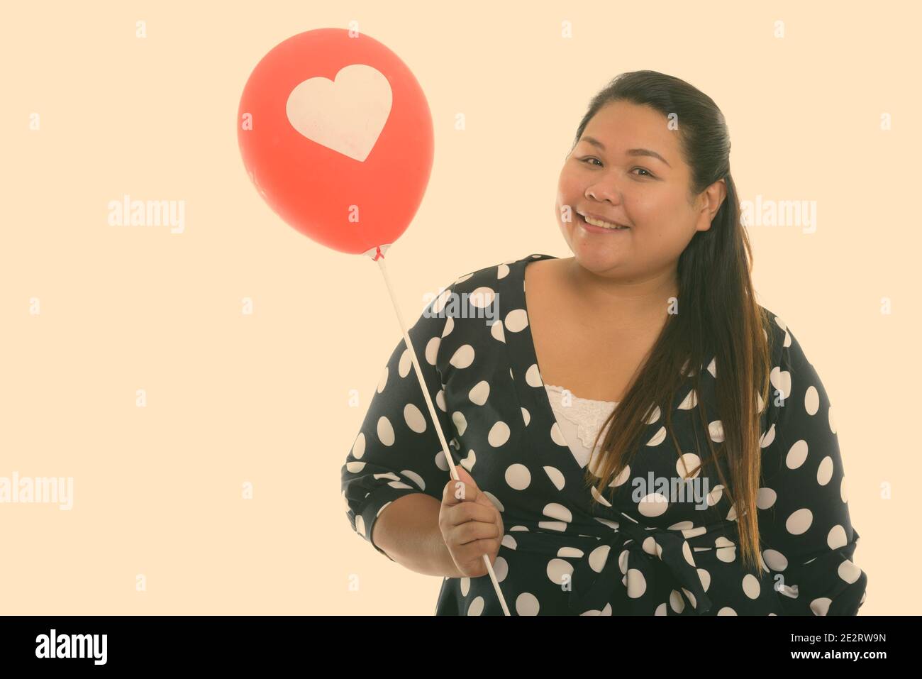 Studio shot der Jungen gerne Fett asiatische Frau lächelnd, während Sie Red Balloon mit Herz anmelden Stockfoto