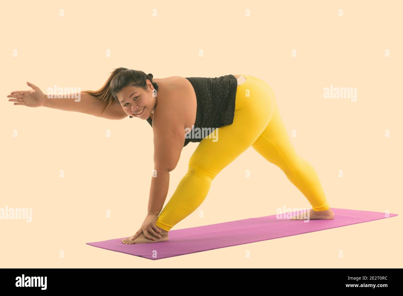 Studio shot der Jungen gerne Fett asiatische Frau lächelnd, während sie zurück biegen und strecken die Beine Stockfoto