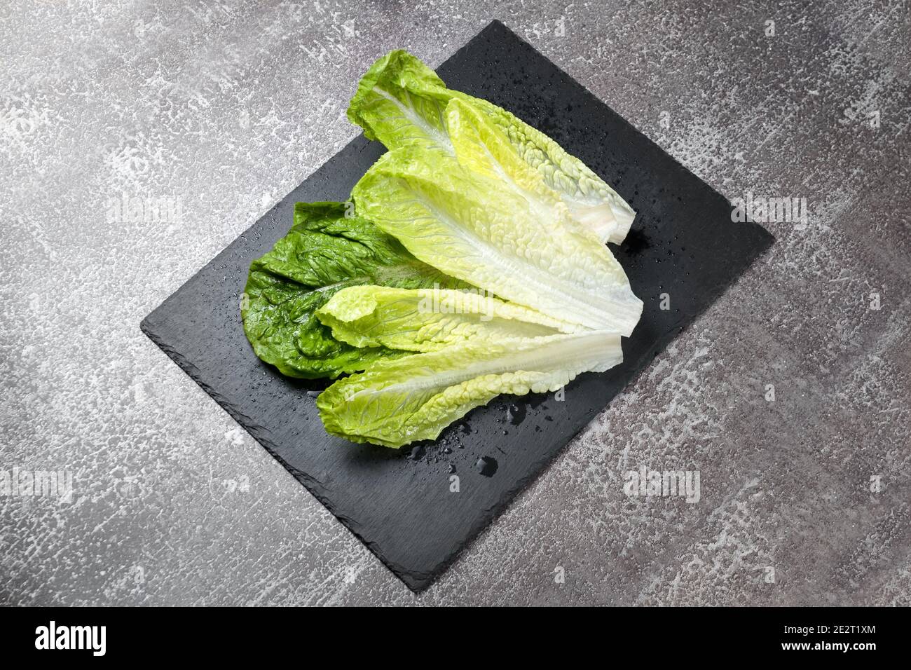 Frisch gewaschenen grünen Salat auf schwarzem Schiefer Schneidebrett bereit zum Kochen. Zutaten zum Kochen, vegetarische Ernährung, gesunde Ernährung Stockfoto