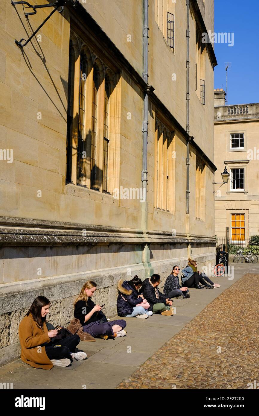 Studenten und Besucher der Oxford University, die einen sonnigen Platz genossen, saßen an einer Wand auf dem Radcliffe Square. Stockfoto