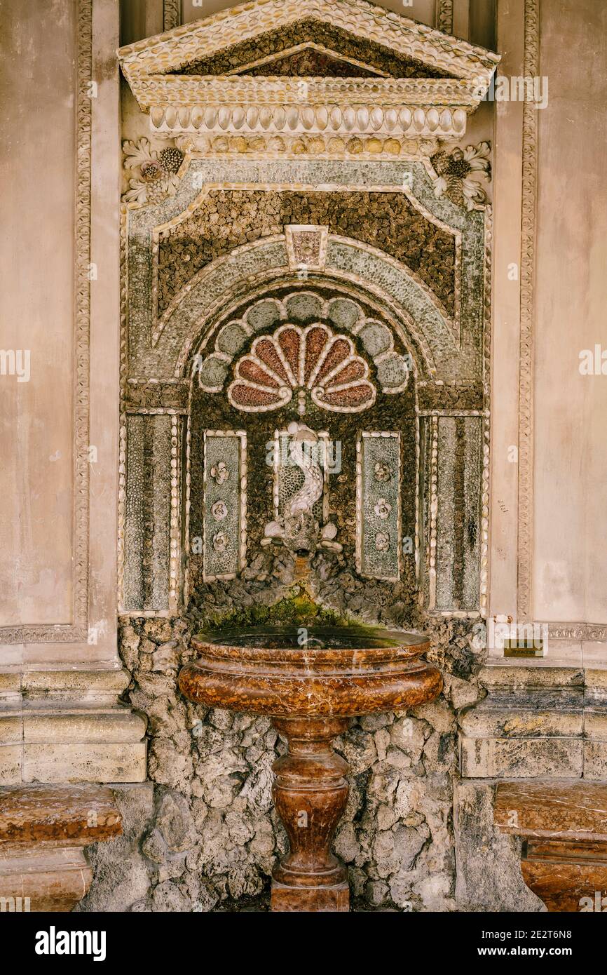 An der Wand montierter Trinkbrunnen im Tempel mit einer Fischfigur über einer braunen Schüssel. Stockfoto