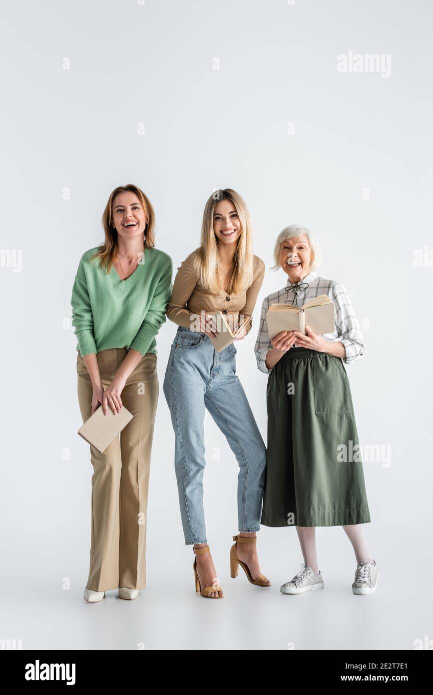 Volle Länge von drei Generationen von glücklichen Frauen mit Büchern Auf Weiß Stockfoto