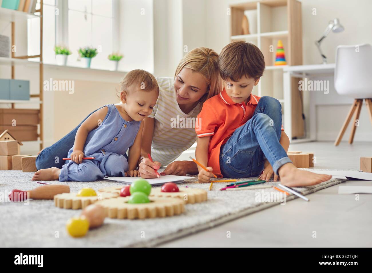Glücklich lächelnde Frau Mutter und Kinder zeichnen zusammen mit Bleistiften Zu Hause Stockfoto