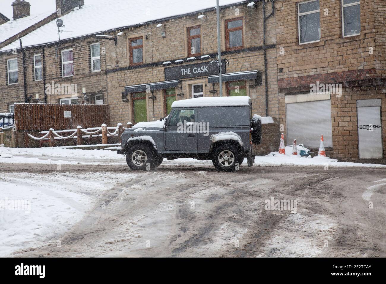 Land Rover fährt sich auf einer verschneiten und vereisten Straße in Kirkheaton Village, Kirklees, West Yorkshire, Großbritannien, durch Schneefall Stockfoto