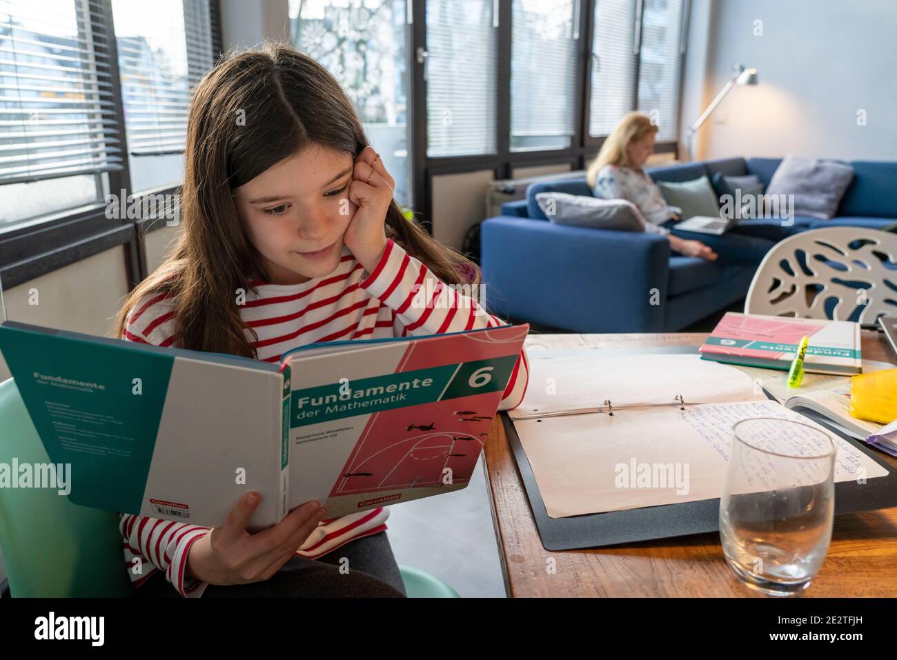 Homeschooling, während der Januar 2021 Sperre, Kinder zu Hause für die Schule studieren, ihre Mutter im Heimbüro arbeiten auf dem Laptop mit vide Stockfoto