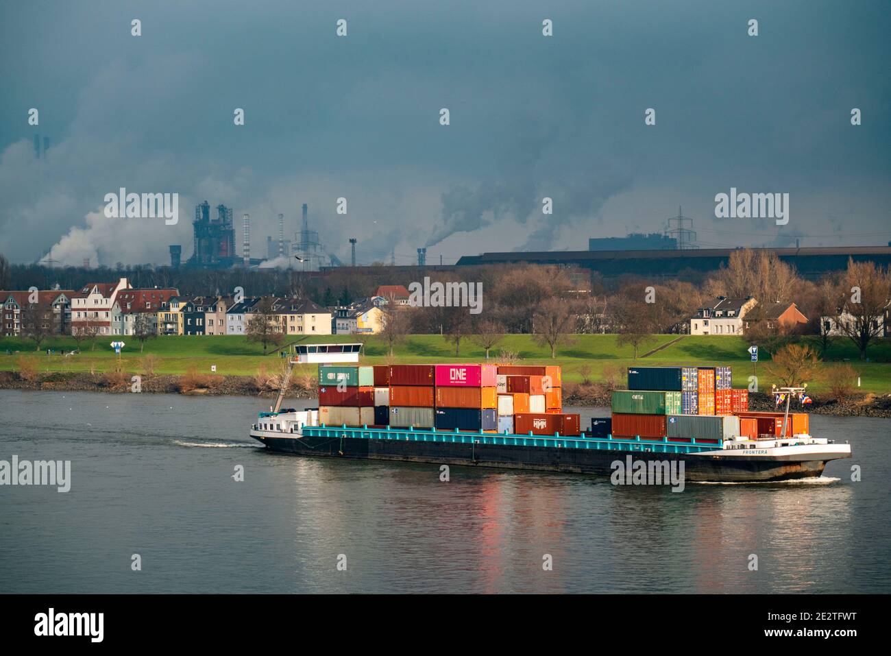 Der Rhein bei Duisburg, Häuser am Rheindeich, Laar, thyssenkrupp Steel Stahlwerk in Bruckhausen, Frachtschiff, Duisburg, NRW, Germa Stockfoto