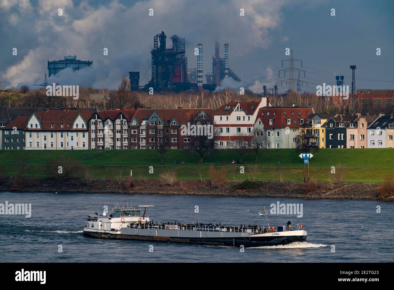 Der Rhein bei Duisburg, Häuser am Rheindeich, Laar, thyssenkrupp Steel Stahlwerk in Bruckhausen, Frachtschiff, Duisburg, NRW, Germa Stockfoto