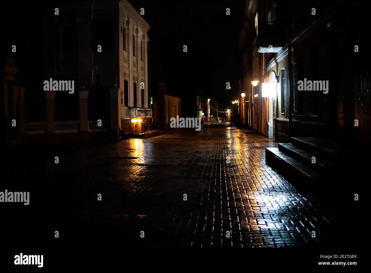 Nachtansicht der Stadtstraße mit einer Ziegelstraße bedeckt mit Eis, Regen. Konzept einer unsicheren Straße für Podeste Stockfoto