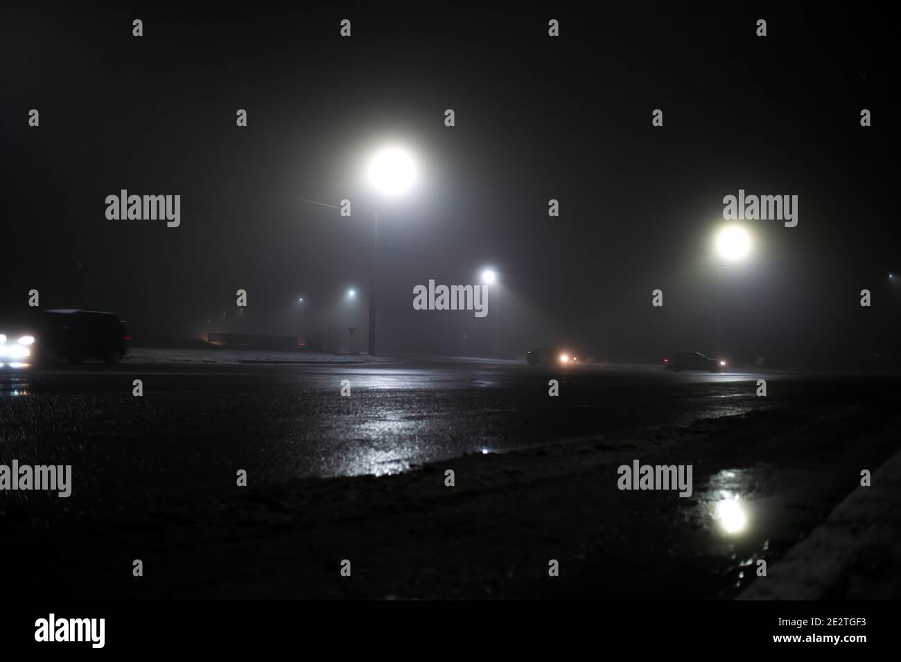 Autos an einer unregulierten Kreuzung im Nebel bei Nacht, schlechte Wetterbedingungen für das Fahren Stockfoto